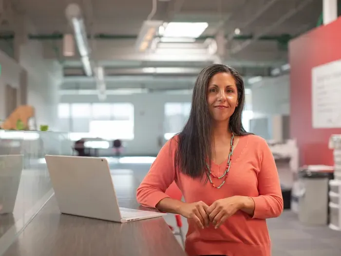 Confident small business owner by a laptop in a bright coworking office, representing local services and community